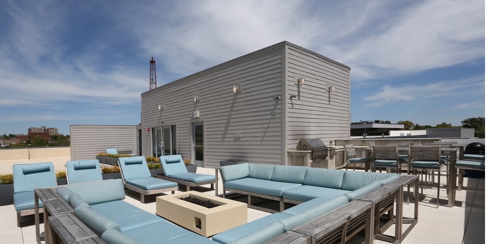 The Bedford Hall rooftop terrace with lounge seating, a fire feature, and grills overlooking the city